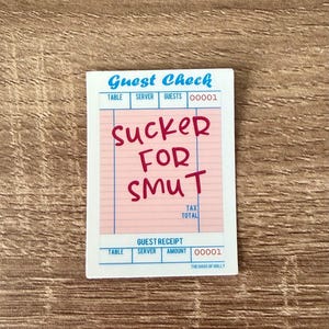 May include: A white and pink guest check with the text "Sucker for Smut" in red. The check has a blue border and the words "Guest Check" at the top. The bottom of the check reads "Guest Receipt".
