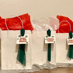 May include: Three white gift bags with green ribbon and festive tags. The tags read "Join the World", "Santa's Favorite Stoner", and "Merry Kushmas".