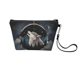 Puede incluir: Una bolsa de maquillaje negra con cremallera con un lobo aullando a la luna en un cielo nocturno estrellado. El lobo está rodeado de árboles y montañas. La bolsa tiene una correa negra.