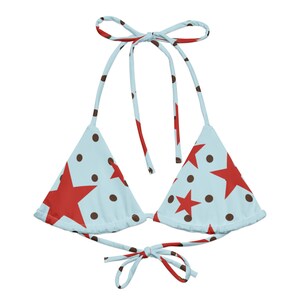 May include: A light blue bikini top with a red star and brown polka dot pattern. The top has tie straps at the neck and back. This swimwear is perfect for a summer day at the beach or pool.