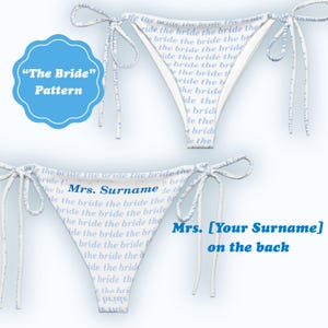 Könnte beinhalten: Weiße Bikinihose mit blauem Text "the bride" und "Mrs. [Your Surname] on the back". Die Bikinihose hat Bindebänder und ein blau-weißes Muster. Ein blauer Kreis zeigt "The Bride" Pattern.