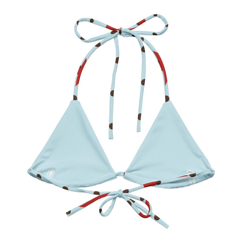 May include: A light blue bikini top with a triangle shape. The straps are light blue with brown polka dots and red accents. The top ties at the neck and back. The bikini top is a swimwear item.