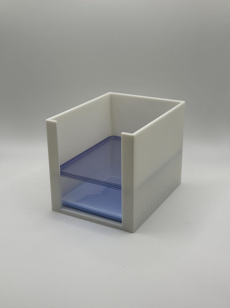 May include: A white, rectangular desk organizer with a blue, transparent shelf. The organizer has an open top and a slot for storing items. The design is minimalist and modern, suitable for office or home use.