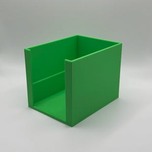 May include: A bright green, rectangular storage container with a simple, open design. The container is made of a solid material and has a smooth, matte finish. The sides are straight and the corners are sharp.