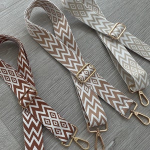 May include: Three patterned fabric straps with gold metal clasps. The straps have a white background with brown geometric designs.