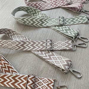 May include: Four different patterned fabric straps with silver metal clasps. The straps are in shades of brown, green, and pink.