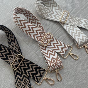 May include: Three patterned fabric straps with gold metal clasps. The straps are brown and white, brown and black, and black and white.