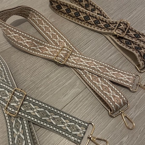 May include: Three woven fabric straps with gold metal clasps. The straps have different patterns and colours, including beige, brown, and green.