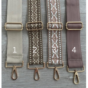 May include: Four different fabric straps with gold metal clasps. The straps are numbered 1 through 4. Strap 1 is beige, strap 2 is brown with a geometric pattern, strap 3 is beige with a pink and white geometric pattern, and strap 4 is a light brown.