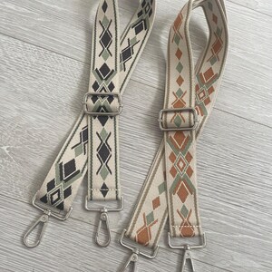 May include: Two adjustable straps with silver clasps. The straps are woven with a geometric pattern in shades of brown, green, and black on a cream background.
