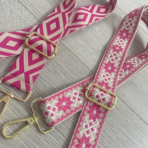 May include: Two pink and beige woven straps with gold metal clasps. The straps have different geometric patterns.