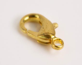 Könnte beinhalten: Ein goldfarbener Karabinerverschluss aus Metall mit Federmechanismus und einer kleinen runden Öse an der Basis zur Befestigung. Das Schmuckelement hat eine glatte, polierte Oberfläche und dient zum Verschließen von Halsketten oder Armbändern.