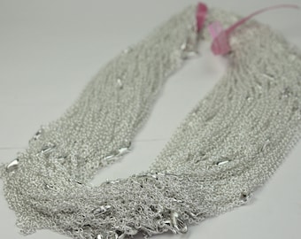 May include: A pile of silver chains with lobster clasps. The chains are arranged in a loose, overlapping pattern.