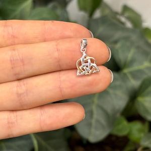 May include: A silver and gold Celtic knot pendant charm in the shape of a triangle. The pendant is intricately designed with a woven knot pattern.