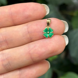 May include: A small gold pendant shaped like a four-leaf clover with green enamel.