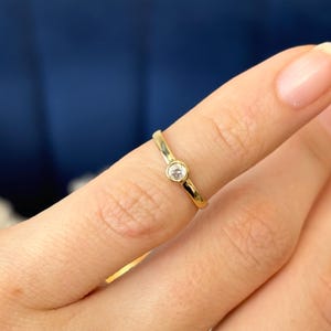 Peut inclure: Une bague simple en or avec une seule petite pierre ronde transparente.