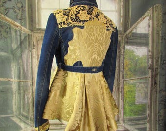 May include: A denim jacket with a gold-colored, patterned fabric back and skirt. The jacket features a lace collar and gold trim on the sleeves. The skirt has a pleated design. The jacket is displayed on a mannequin.