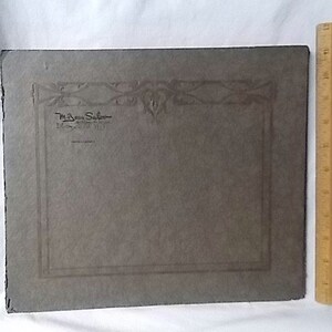 May include: A vintage gray photograph with decorative border and text from "M. Ben Salon, Dayton, Ohio". A wooden ruler, approximately 12 inches long, is positioned vertically next to the photograph.