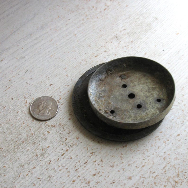 Puede incluir: Un dosel de techo de metal desgastado con tres agujeros, apilado sobre una base oscura y texturizada. Una moneda de veinticinco centavos estadounidense est&aacute; al lado del dosel para comparar el tama&ntilde;o. El dosel tiene una apariencia desgastada y envejecida.