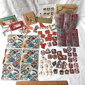 May include: A collection of vintage Christmas paper ephemera including gift tags, stickers, and wrapping paper sheets featuring Santa Claus and holiday motifs. A wooden ruler at the bottom shows a scale of 30 cm for size reference.