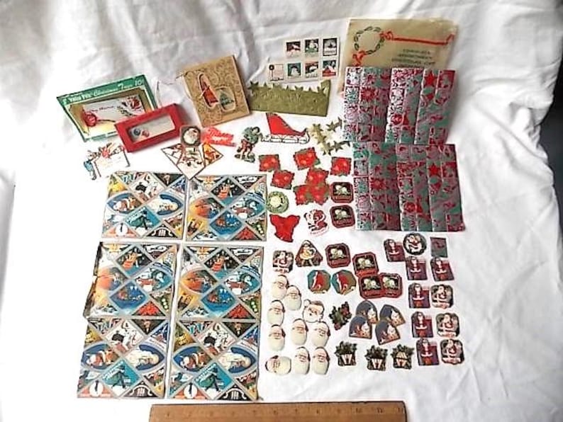 May include: A collection of vintage Christmas paper ephemera including gift tags, stickers, and wrapping paper sheets featuring Santa Claus and holiday motifs. A wooden ruler at the bottom shows a scale of 30 cm for size reference.