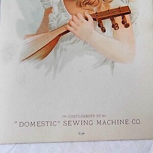 Może przedstawiać: Vintage ilustracja kobiety z blond włosami grającej na instrumencie strunowym. Ma na sobie białą sukienkę i turkusowy naszyjnik. Tekst na dole brzmi "COMPLIMENTS OF" i "DOMESTIC" SEWING MACHINE CO.
