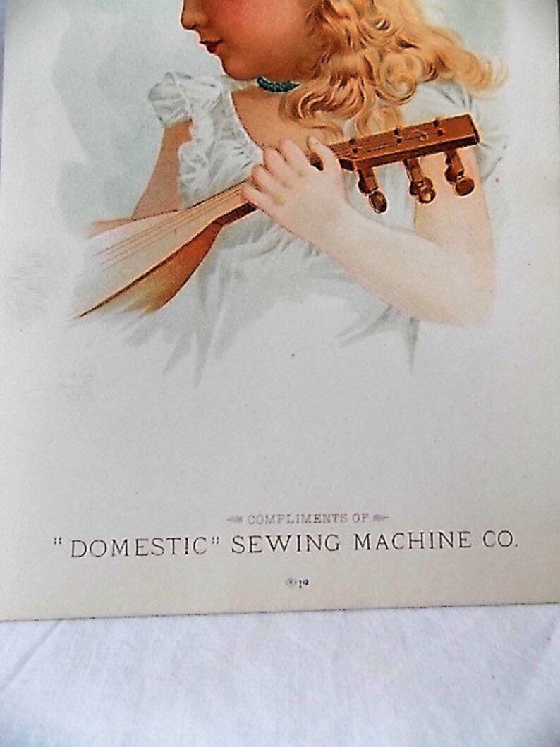 Może przedstawiać: Vintage ilustracja kobiety z blond włosami grającej na instrumencie strunowym. Ma na sobie białą sukienkę i turkusowy naszyjnik. Tekst na dole brzmi "COMPLIMENTS OF" i "DOMESTIC" SEWING MACHINE CO.