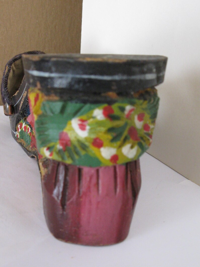 Peut inclure: Une figurine de chaussure en bois d&eacute;corative avec un talon et une semelle noirs. La partie sup&eacute;rieure est peinte d'une bande verte vive orn&eacute;e de motifs floraux rouges et blancs, tandis que le bas du talon est fini en rose fonc&eacute; uni.