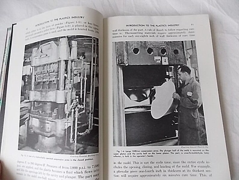 Peut inclure: Double page d'un livre ancien intitul&eacute; &laquo; Introduction &agrave; l'industrie des plastiques &raquo;. La page de gauche montre un sch&eacute;ma d'une presse &agrave; compression hydraulique. La page de droite montre un homme utilisant une grande presse.