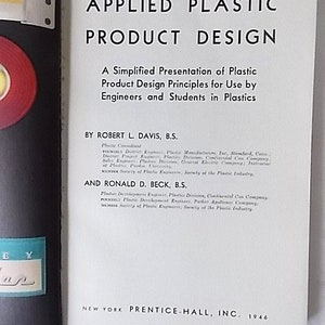 Peut inclure: Livre ouvert intitul&eacute; "APPLIED PLASTIC PRODUCT DESIGN" avec du texte de Robert L. Davis et Ronald D. Beck. Publi&eacute; par Prentice-Hall, Inc. en 1946. La couverture du livre est blanche avec du texte noir.