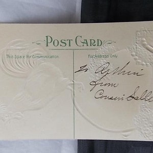 May include: A cream-colored vintage postcard with green text reading Post Card, This Space for Communication, and For Address Only. The card features an embossed rooster design on the left and handwritten black ink cursive script in the center.