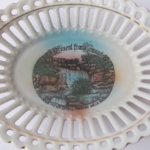 May include: White, oval-shaped, openwork porcelain dish with a gold rim. The center features a colorful image of a waterfall and the text "present from Ramsgate" and "THE WATERFALL MARINE WALK".