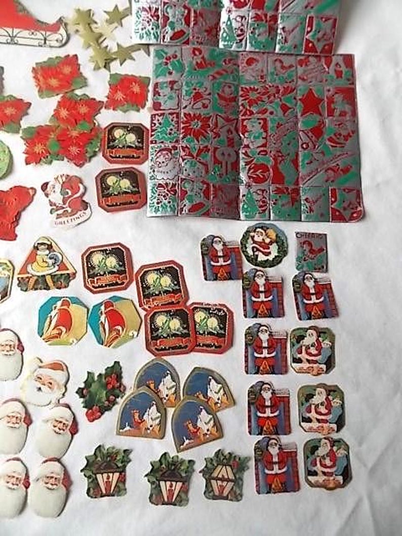 May include: A collection of vintage Christmas paper ephemera including die-cut Santa Claus figures, poinsettia shapes, gold stars, and a large rectangular sheet featuring a repeating grid of festive holiday motifs in red, green, and silver foil.