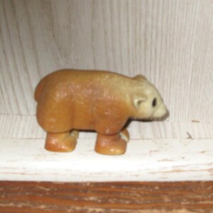 Peut inclure: Petite figurine d'ours brun avec une t&ecirc;te beige clair et de petits yeux noirs. L'ours est &agrave; quatre pattes, avec un corps arrondi et des pattes courtes. La figurine est faite d'un mat&eacute;riau solide et a une finition lisse.