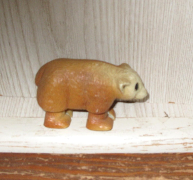 Peut inclure: Petite figurine d'ours brun avec une t&ecirc;te beige clair et de petits yeux noirs. L'ours est &agrave; quatre pattes, avec un corps arrondi et des pattes courtes. La figurine est faite d'un mat&eacute;riau solide et a une finition lisse.