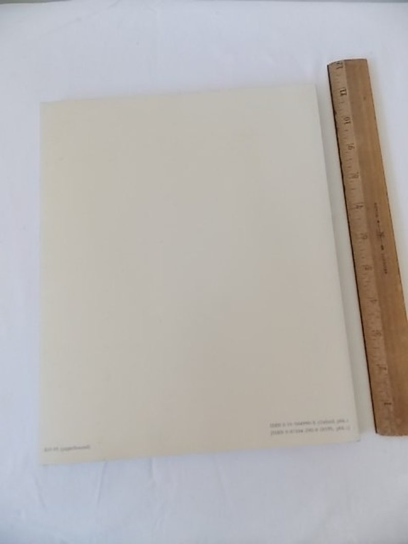 Pode incluir: Uma folha de papel retangular creme com texto no canto inferior direito. Uma r&eacute;gua de madeira com marca&ccedil;&otilde;es em polegadas &eacute; posicionada verticalmente ao longo da borda direita do papel.