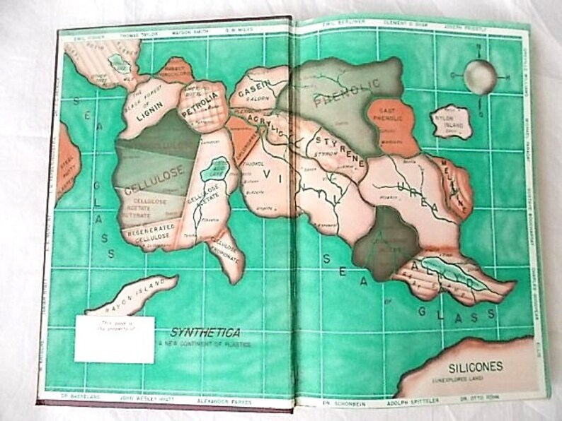 Peut inclure: Livre ouvert avec une illustration de carte intitul&eacute;e "Synthetica: Un nouveau continent de plastiques". La carte pr&eacute;sente des masses terrestres nomm&eacute;es Cellulose et Silicones, sur un fond quadrill&eacute; vert.