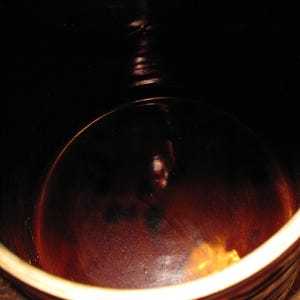 May include: A close-up shot of the interior of a brown ceramic crock. The interior is dark, with a glossy finish. The rim of the crock is a lighter brown color.
