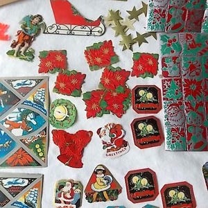 May include: A collection of vintage Christmas paper ephemera including die-cut poinsettias, Santa Claus figures, a red sleigh, gold foil stars, and rectangular gift tags with candle illustrations, all featuring festive red, green, and gold colours.