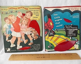 May include: Two vintage Star-Bright Musical Pack O' Fun activity sets featuring Nursery Games and The Little Engine That Could, each with a red vinyl record, positioned above a 12-inch wooden ruler on a white surface.