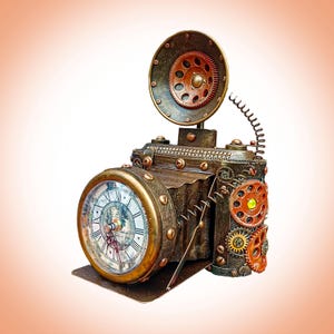 Puede incluir: Una escultura de cámara de estilo steampunk con una esfera de reloj y engranajes expuestos. El cuerpo de color bronce presenta remaches de cobre y un flash circular. La esfera del reloj tiene números romanos. Una pieza decorativa.