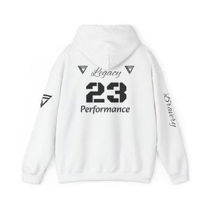 May include: White hoodie with black text and graphics. The back features the word "Legacy" above the number "23" and the word "Performance". The right sleeve has the word "Bravery". A triangle graphic is on the left sleeve.