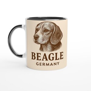 Könnte beinhalten: Keramikbecher mit schwarzem Henkel und Rand. Er zeigt eine detaillierte braune Illustration des Kopfes eines Beagles mit den Wörtern "BEAGLE" und "GERMANY" darunter.