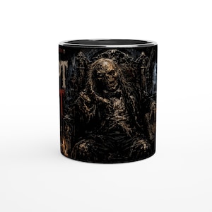 Może przedstawiać: Cylindryczny ceramiczny kubek z ciemną, szczegółową ilustracją szkieletowej postaci w garniturze siedzącej na ozdobnym tronie. Grafika wykorzystuje paletę głębokich brązów, czerni i stonowanych szarości, z częściowo widocznym tekstem po lewej.
