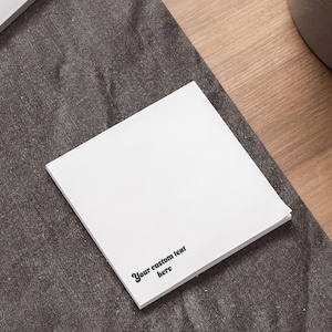 May include: A white square sticky note with the text "Your custom text here" printed in black.