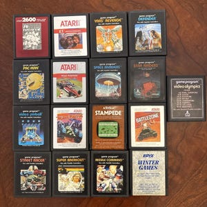 Puede incluir: Una colección de cartuchos de videojuegos Atari 2600. Los juegos incluyen Pac-Man, E.T., Yars' Revenge, Defender, Pole Position, Space Invaders, Star Raiders, Video Pinball y Winter Games. Los cartuchos son negros con arte de juego colorido.