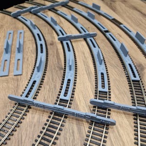 May include: A set of grey plastic track gauge tools for model railway. The tools are labelled with the measurement "31mm".