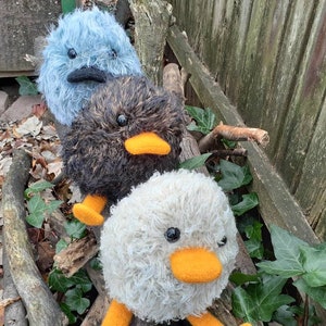 Peut inclure: Trois jouets en peluche moelleux en forme d'oiseaux. Le premier oiseau est bleu avec un bec et des yeux noirs. Le deuxi&egrave;me oiseau est brun avec un bec et des yeux noirs et un bec orange. Le troisi&egrave;me oiseau est blanc avec un bec et des yeux noirs et un bec orange.