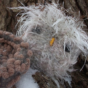 Pu&ograve; includere: Un gufo di peluche bianco e marrone a forma di gufo con un becco giallo e occhi neri. Il gufo &egrave; seduto su un tronco d'albero marrone.