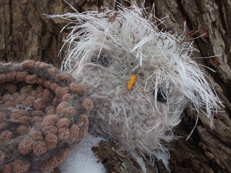 Pu&ograve; includere: Un gufo di peluche bianco e marrone a forma di gufo con un becco giallo e occhi neri. Il gufo &egrave; seduto su un tronco d'albero marrone.